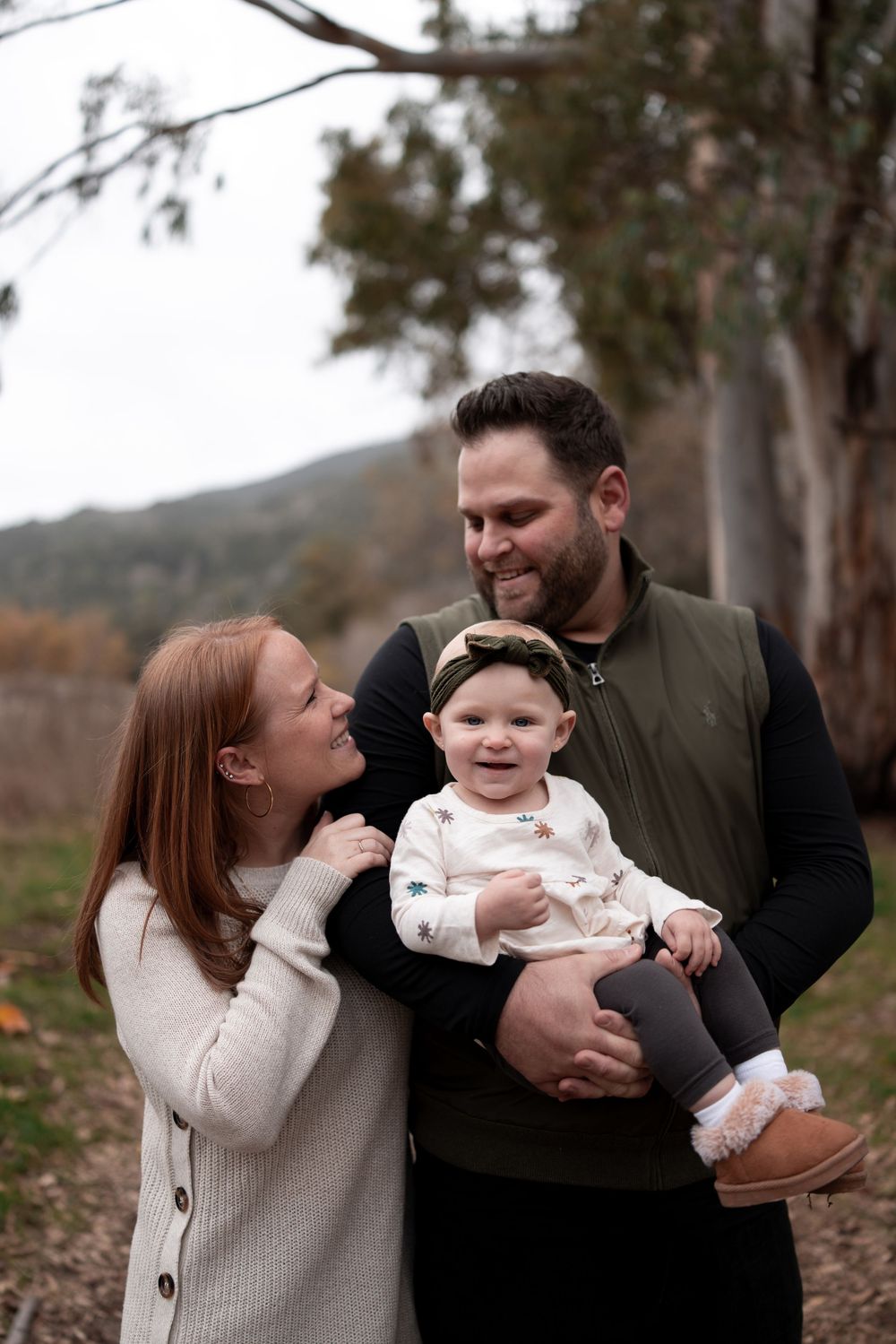 Family enjoying a tender moment together outdoors in a wooded setting.