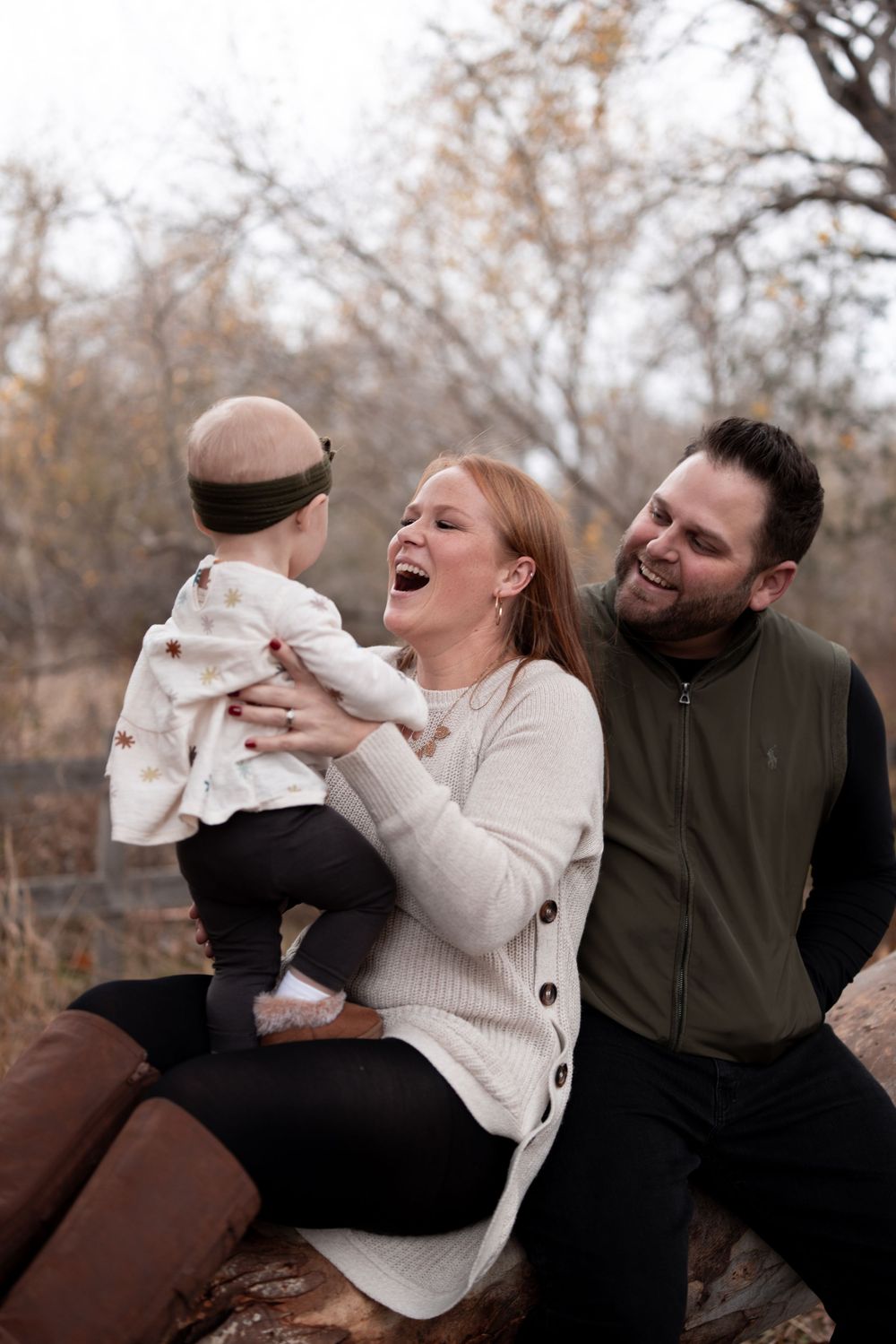 Family shares a candid laughing moment together while sitting on rocks during an outdoor photo session.