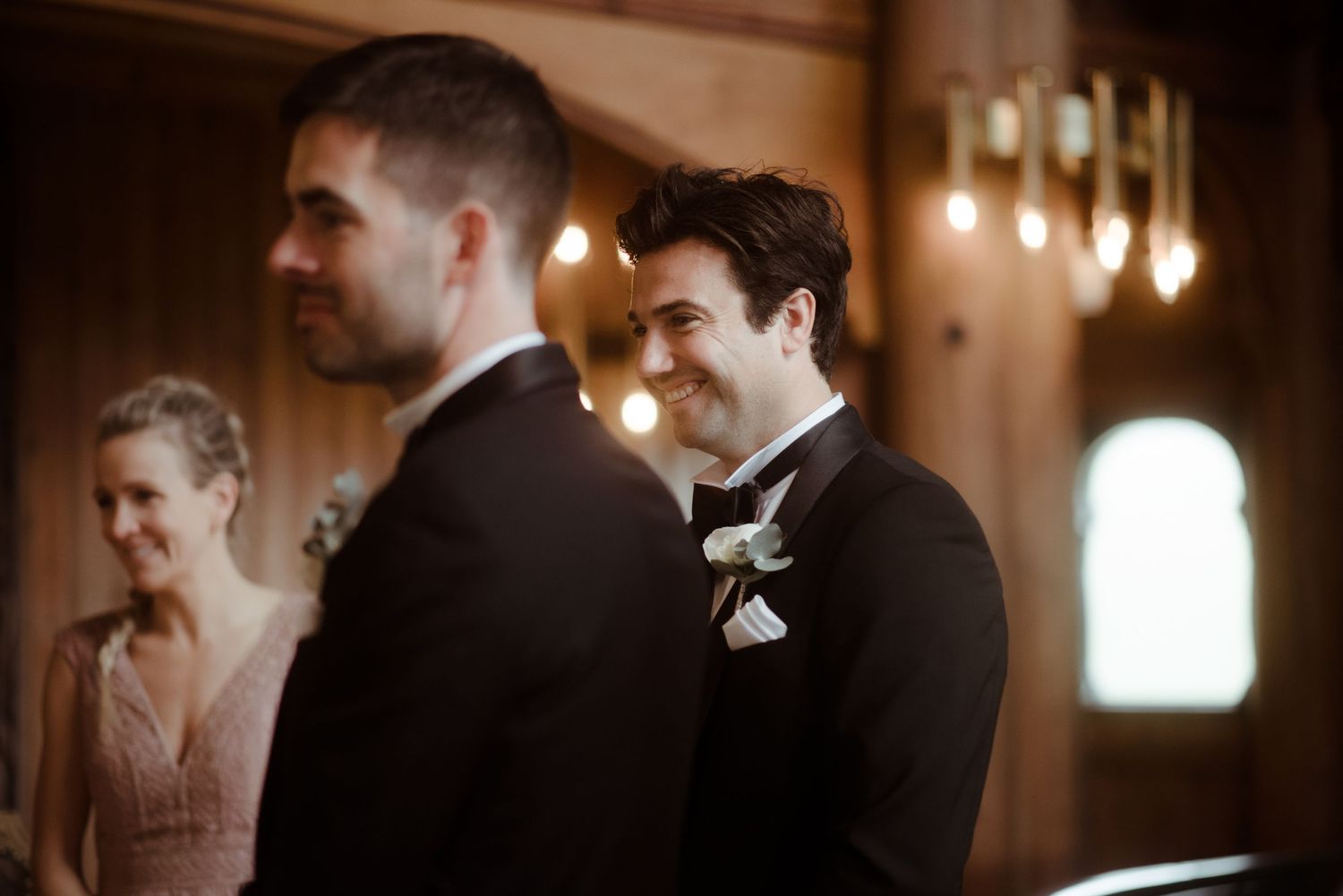 Wedding party members standing at the altar in an elegantly lit ceremony space.