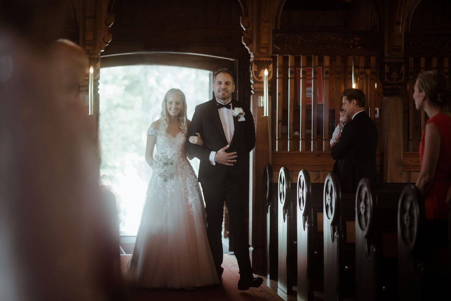 A wedding processional captured in a beautifully lit church aisle.