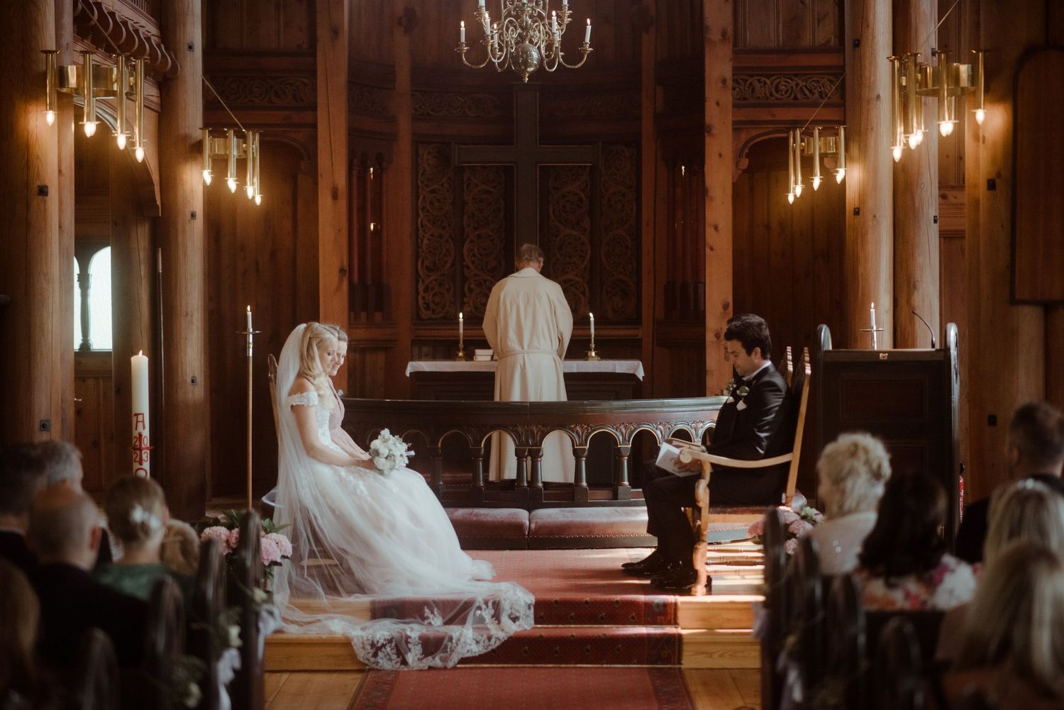 Intimate church wedding ceremony with warm lighting and wooden paneled walls.