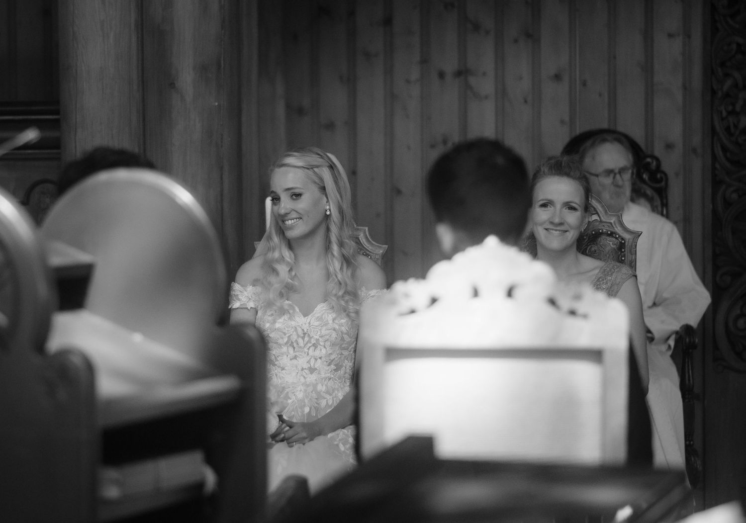 Black and white candid shot of wedding guests during a church ceremony.