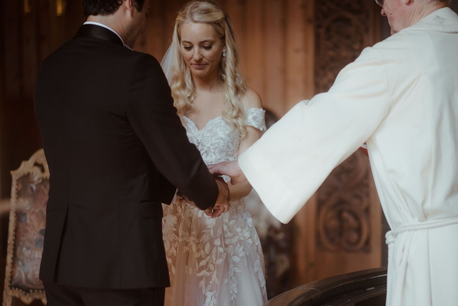 Close-up of wedding ceremony exchange between couple and officiant at altar.