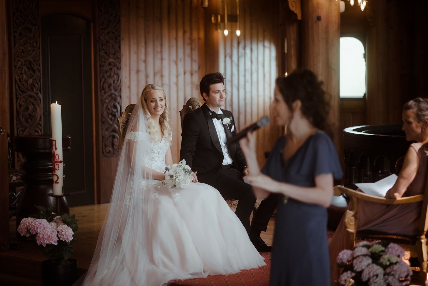 Intimate wedding ceremony taking place in an elegant wood-paneled room with floral decorations.