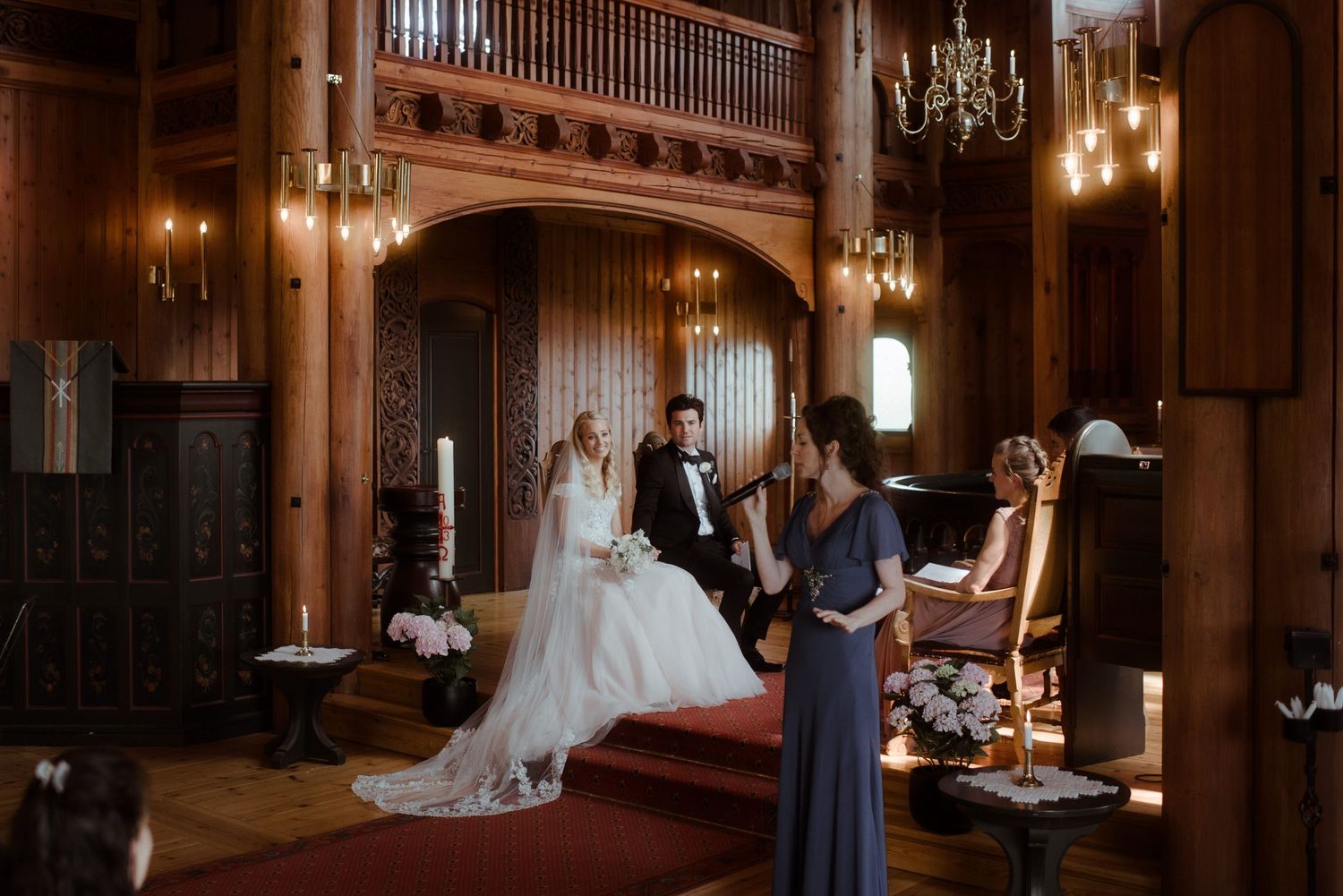 Wedding ceremony in a historic wooden church with chandelier lighting and ornate details.