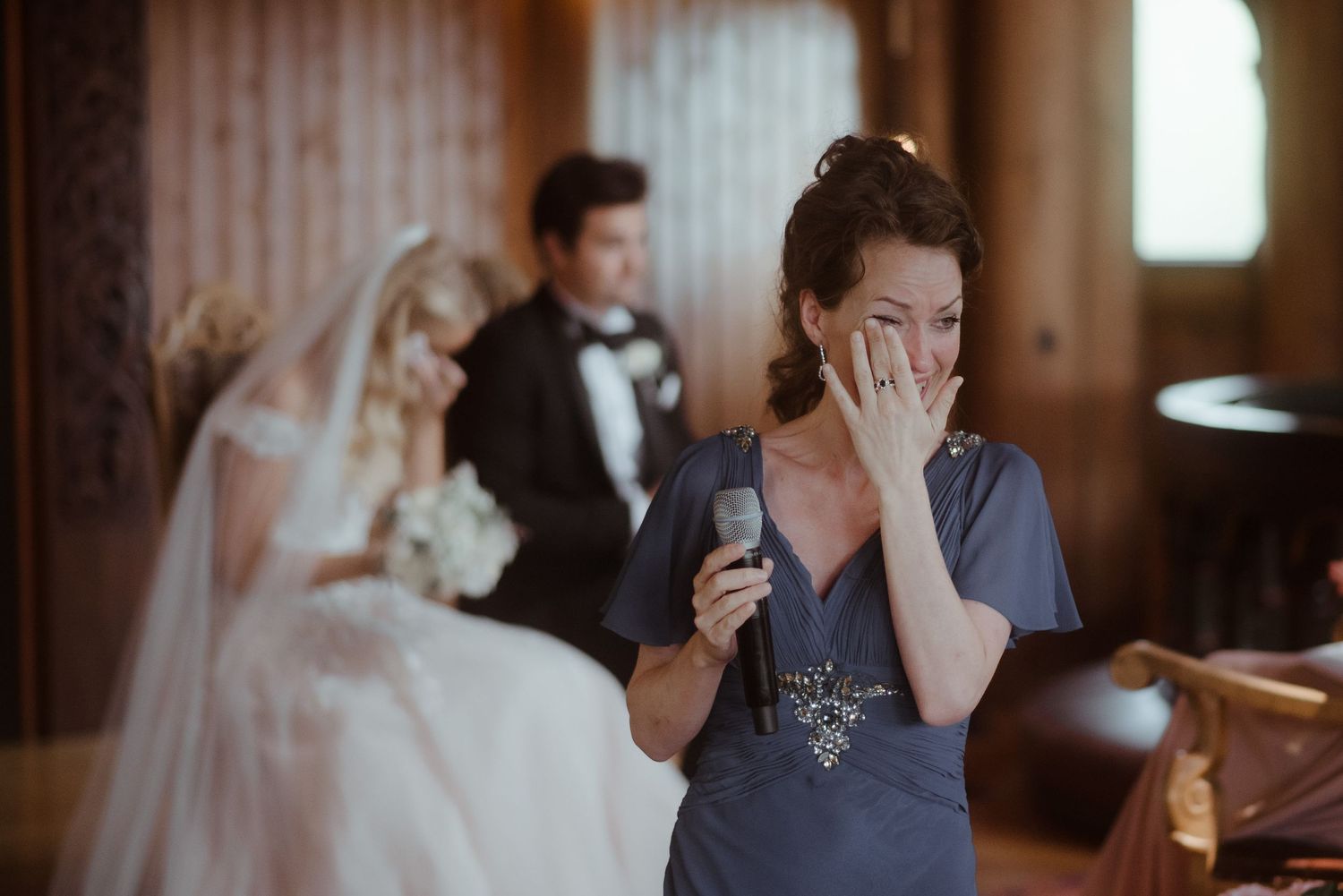 Emotional candid moment captured during an elegant indoor wedding ceremony.