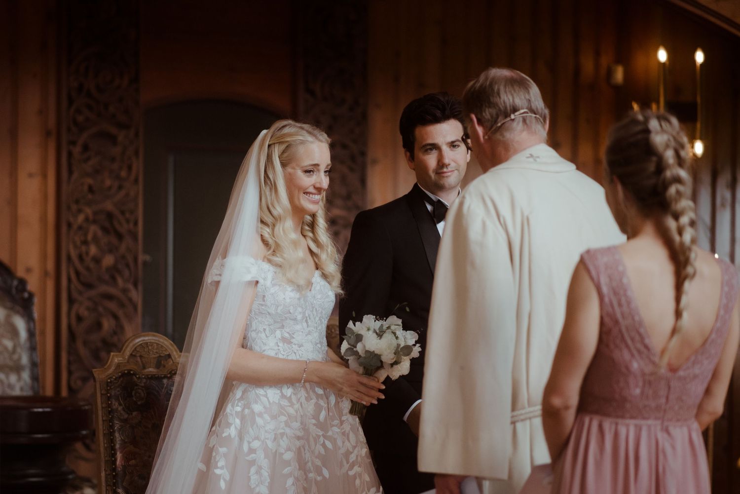 An elegant church wedding ceremony with a bride in a lace gown standing at the altar.