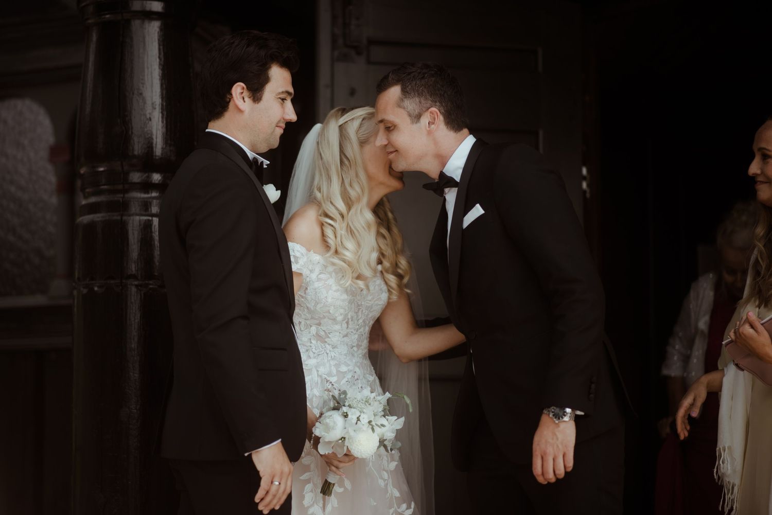Intimate wedding moment captured between couple and wedding party members.