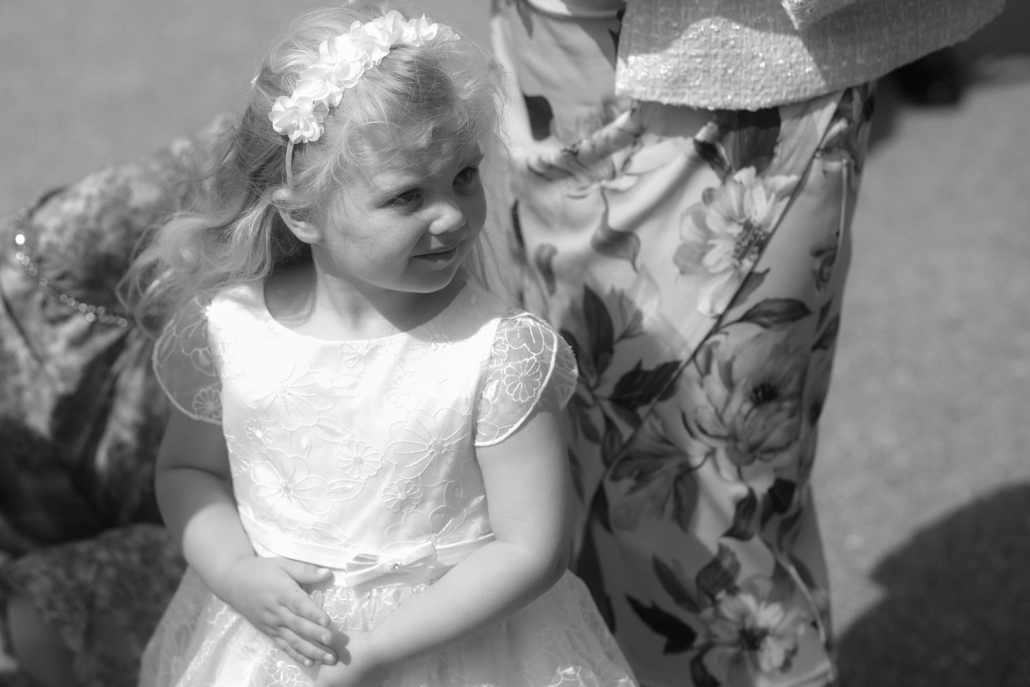Black and white portrait of young flowergirl in white dress looking to the side.