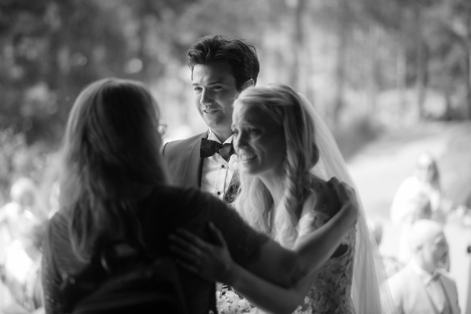 A tender moment between a couple and their officiant during an outdoor wedding ceremony.