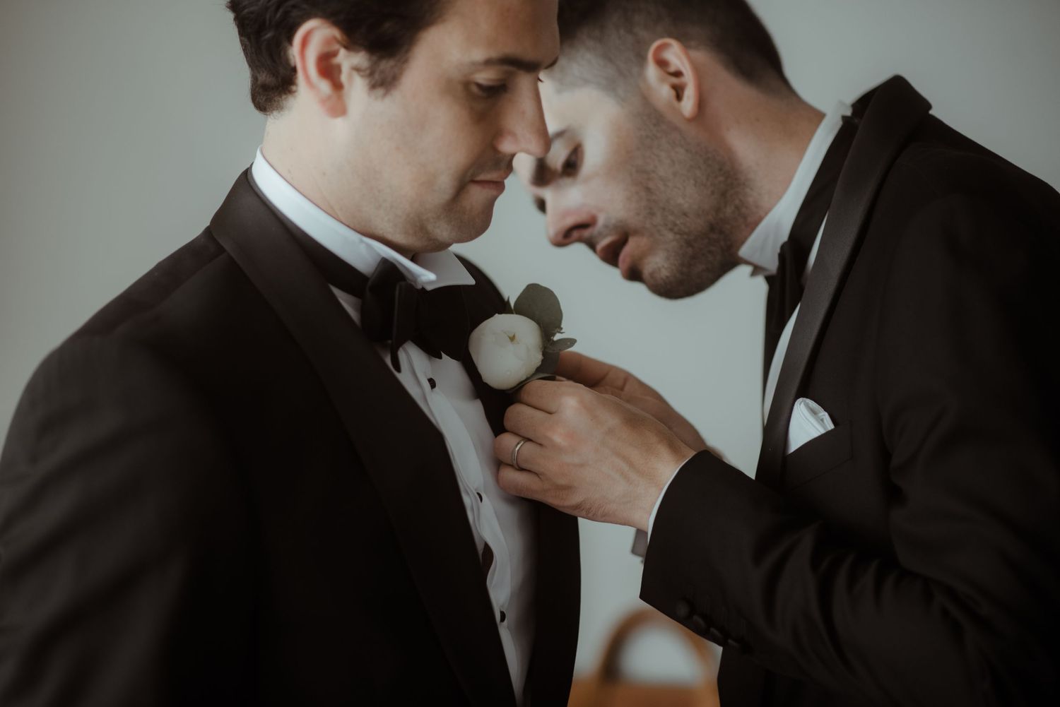 Intimate moment between two people in formal suits with boutonniere flowers.