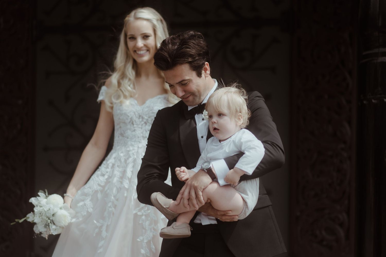 A wedding portrait featuring a couple with a small child in formal attire.