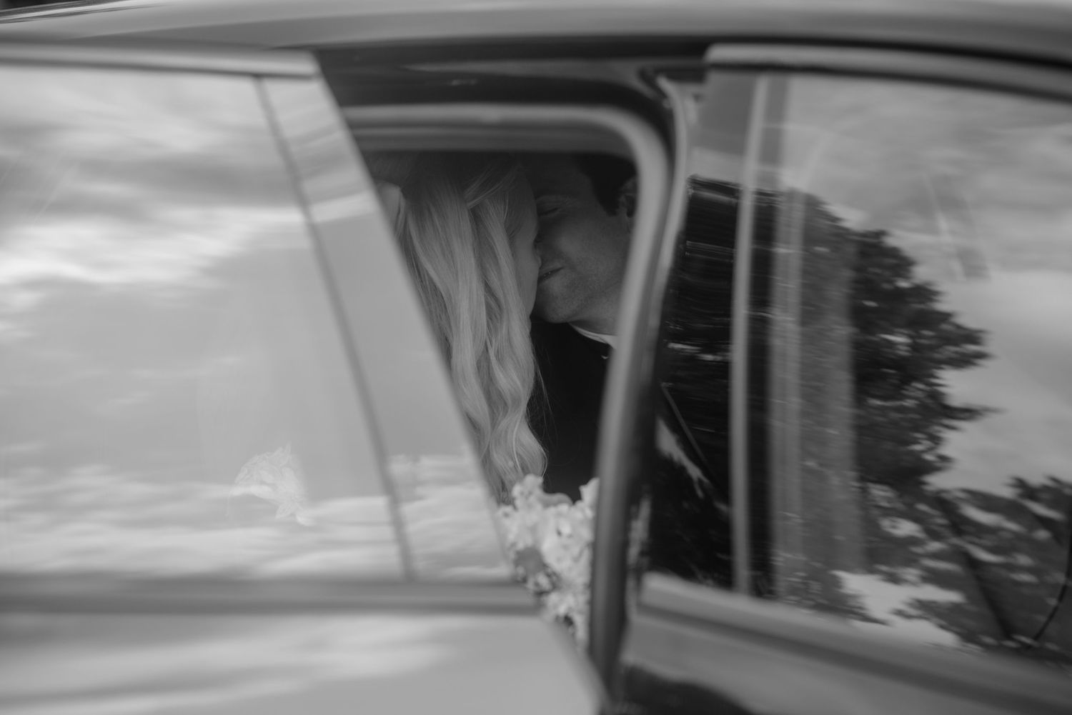 A black and white shot through a car window on a wedding day.