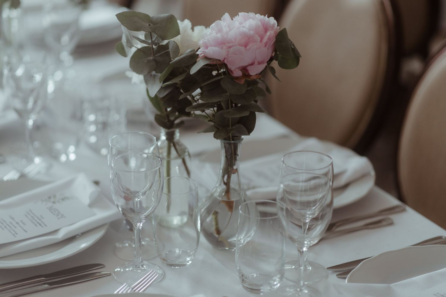 Elegant table setting with pink rose centerpiece in glass vase.