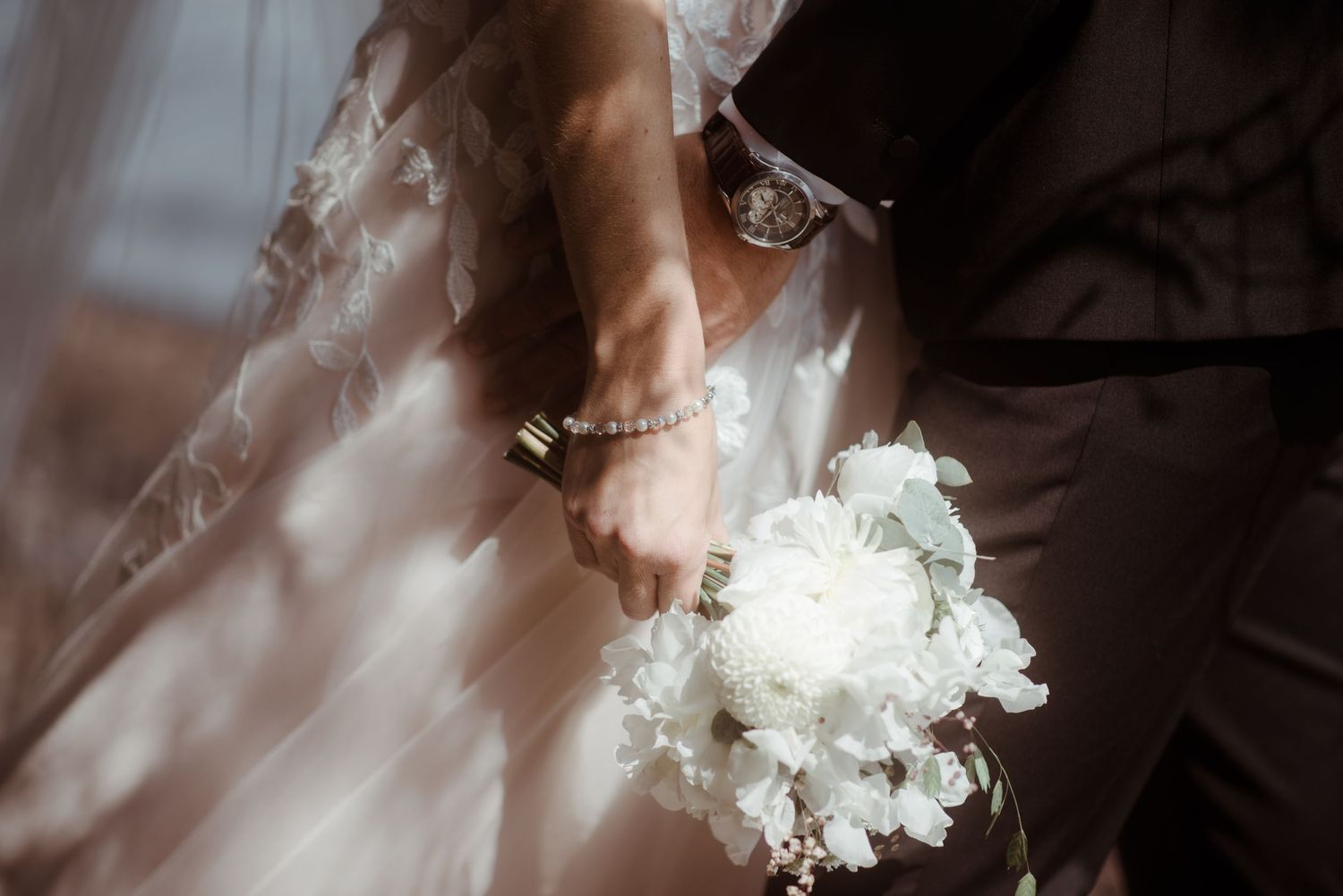 A delicate white bridal bouquet and wedding dress details captured in soft natural light.