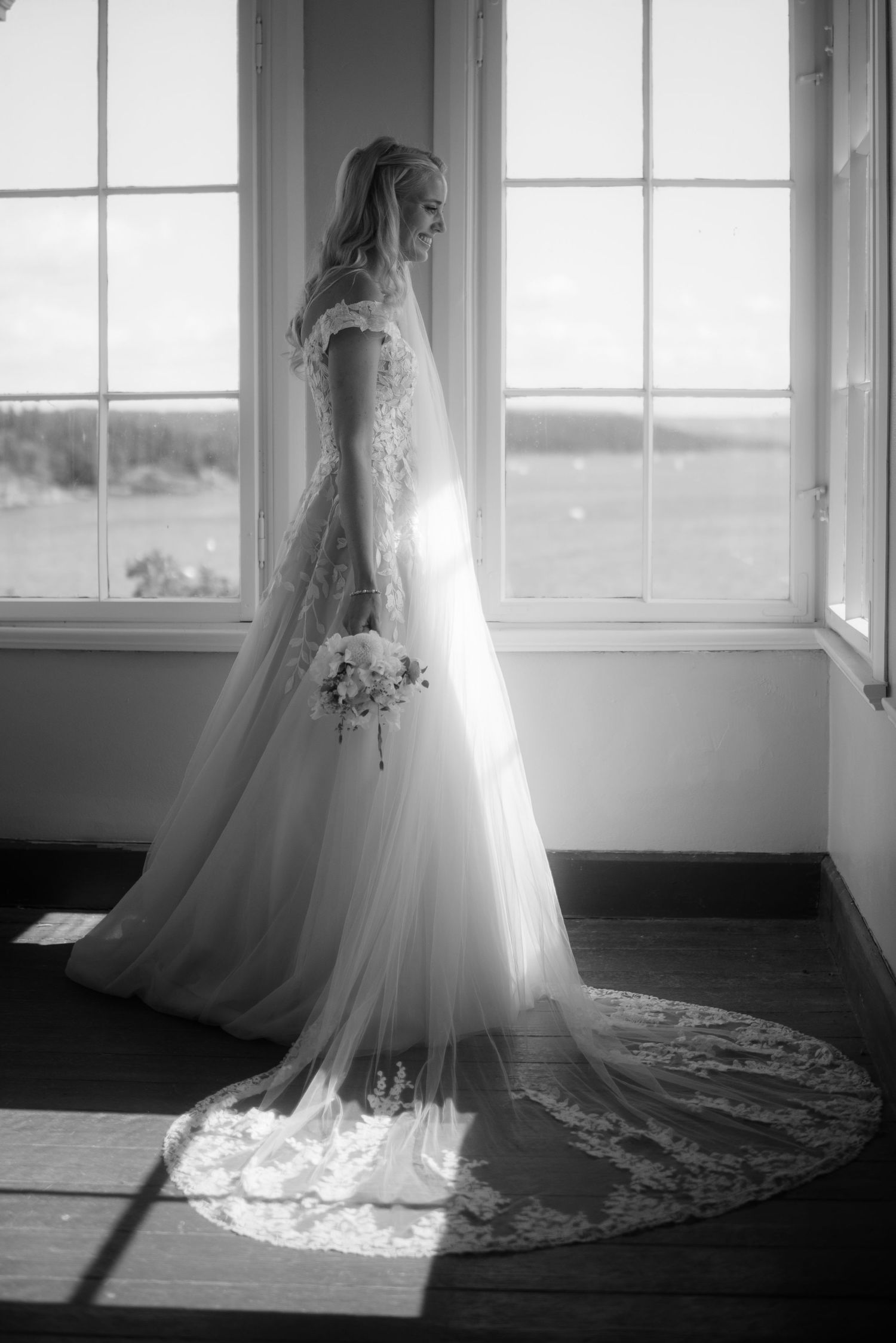 Black and white photo of wedding dress silhouetted against bright windows.