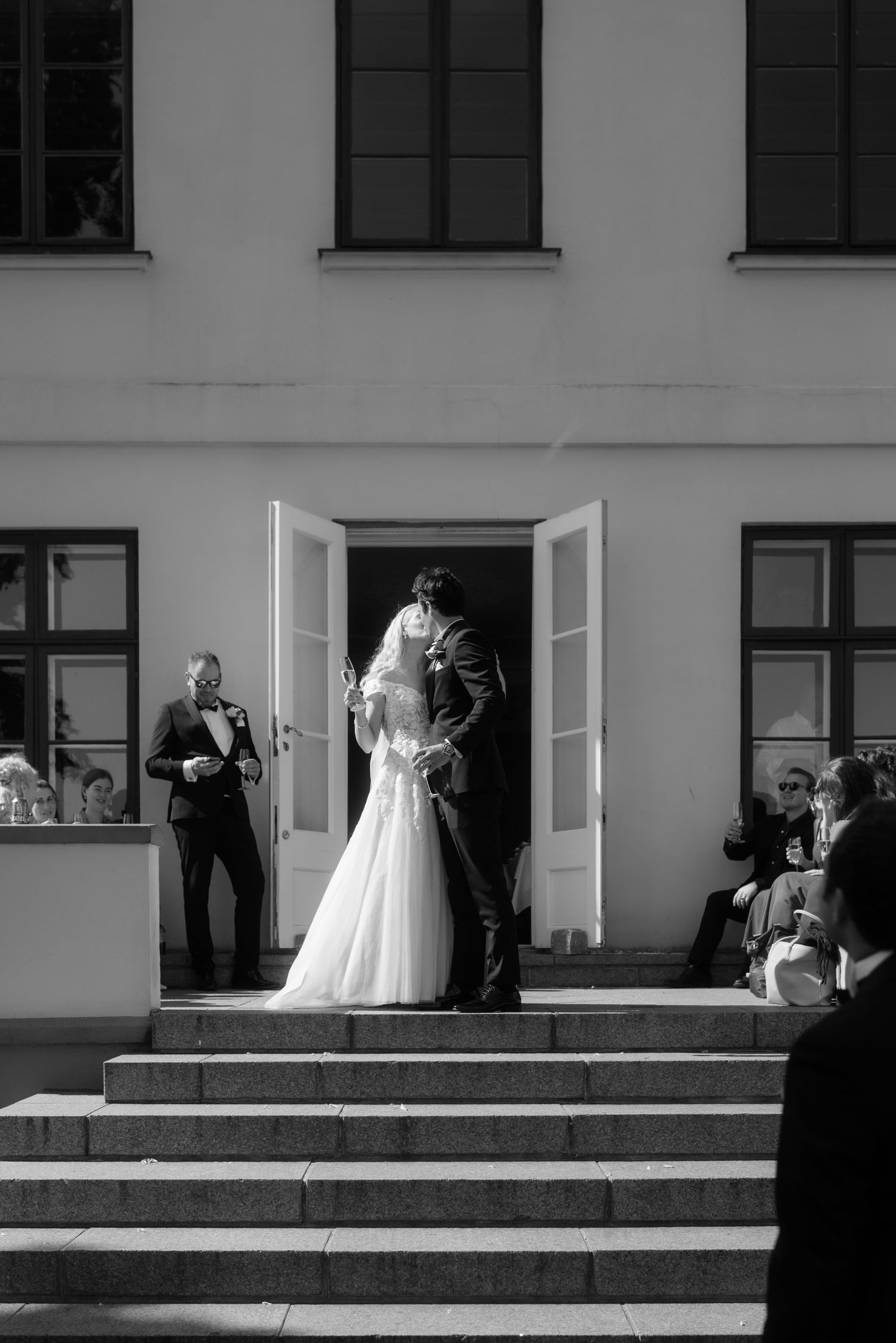 A black and white photo of a wedding ceremony exit on stone steps of a white building.