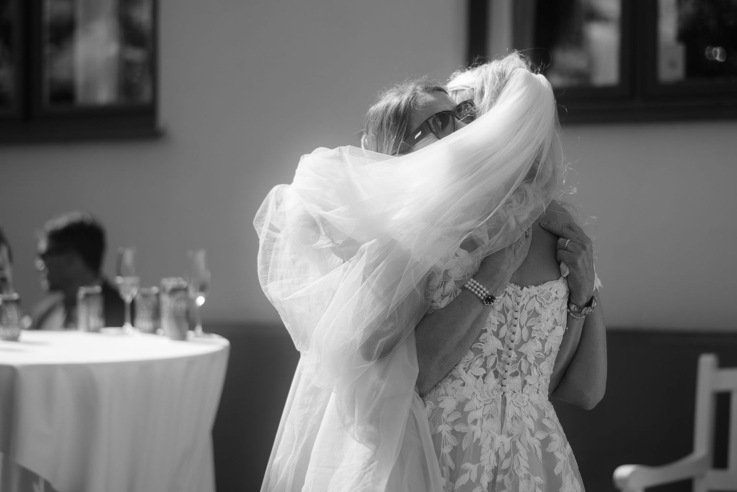 A flowing veil creates an ethereal effect in this black and white wedding photograph.