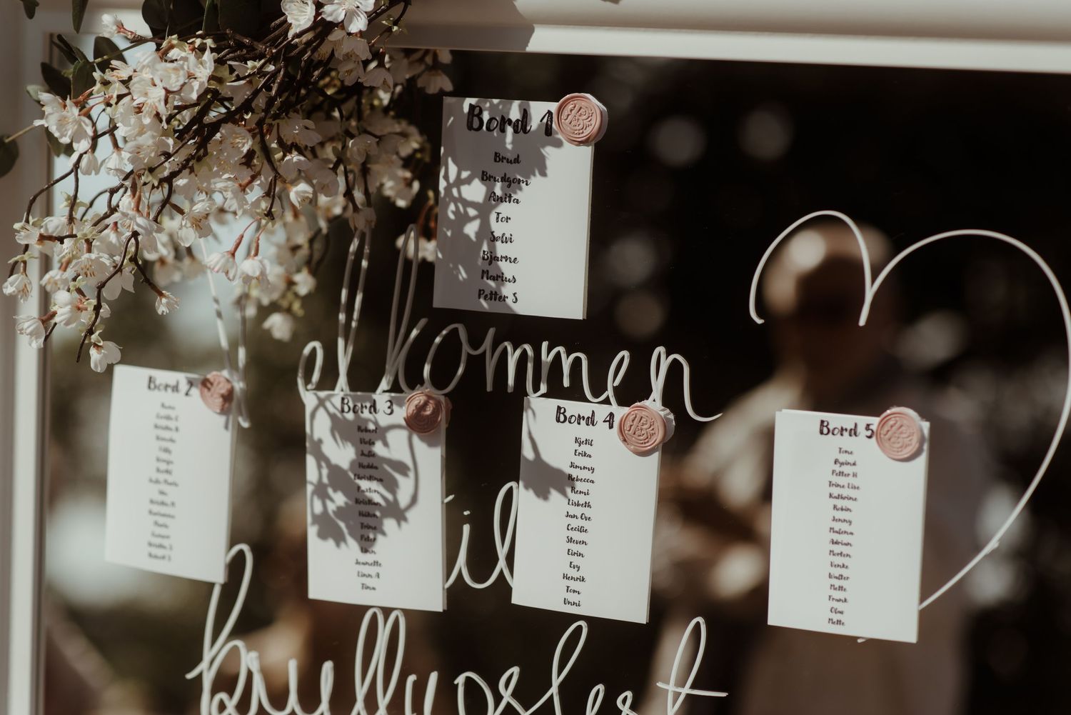 A rustic wedding seating chart display with handwritten name cards and floral decorations.