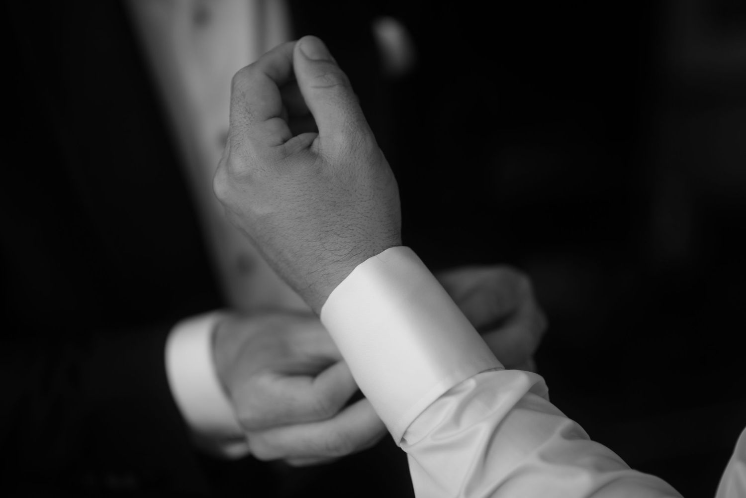 Close-up black and white shot of dress shirt cuff being adjusted.