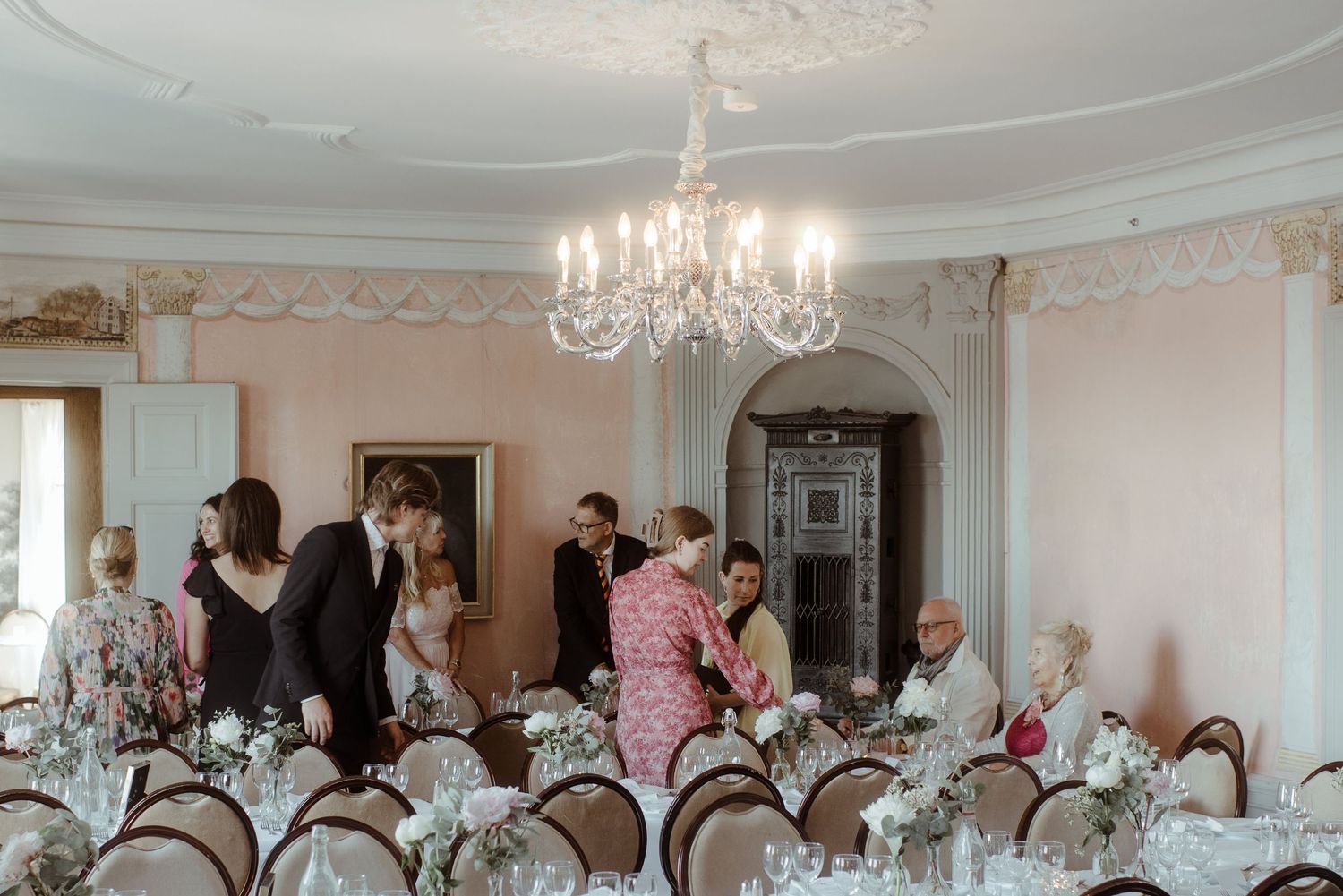 Elegant dining room with chandelier and guests preparing for a formal event.