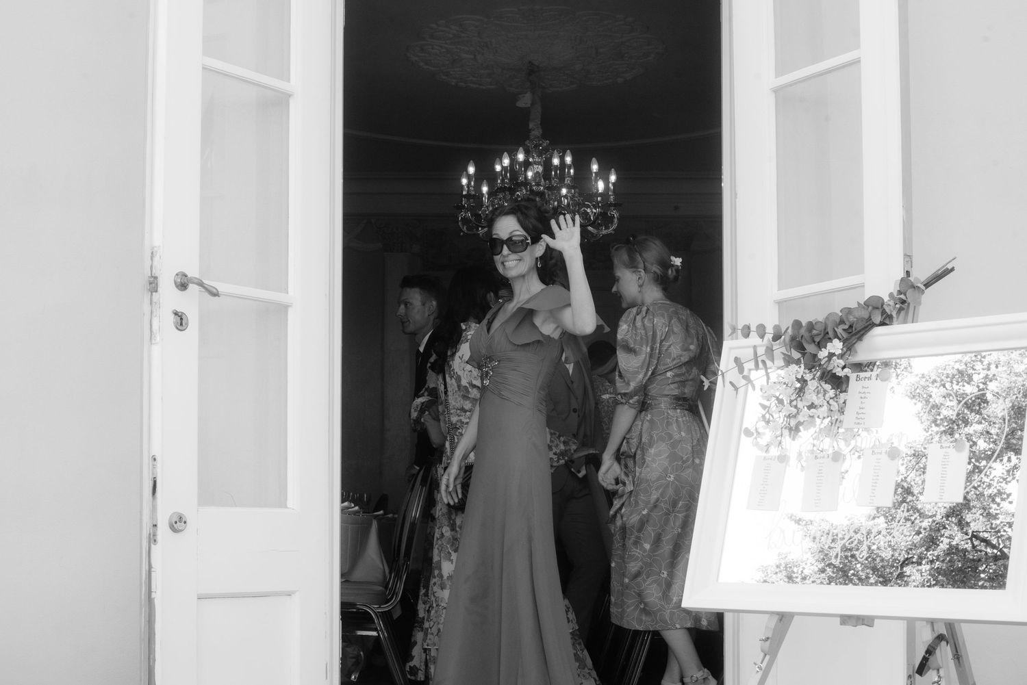 Black and white image of a formal event through a doorway with white trim.