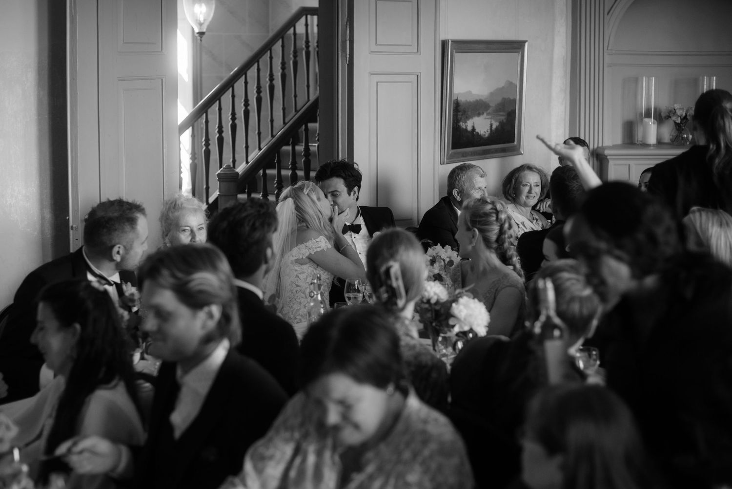A crowded indoor gathering with guests mingling in formal attire at an elegant venue.