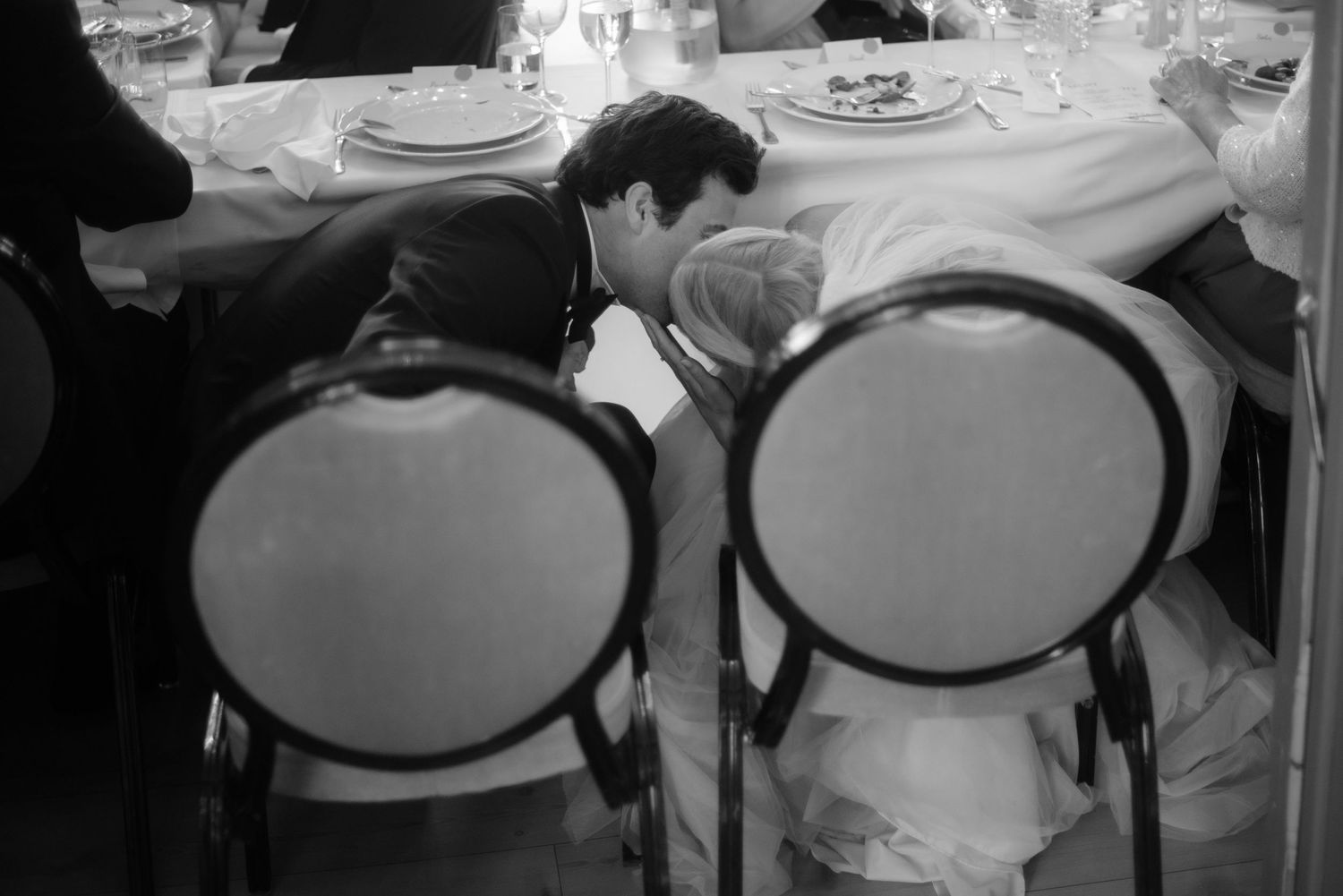 Formal place settings at a banquet with elegant chairs and white tablecloths.