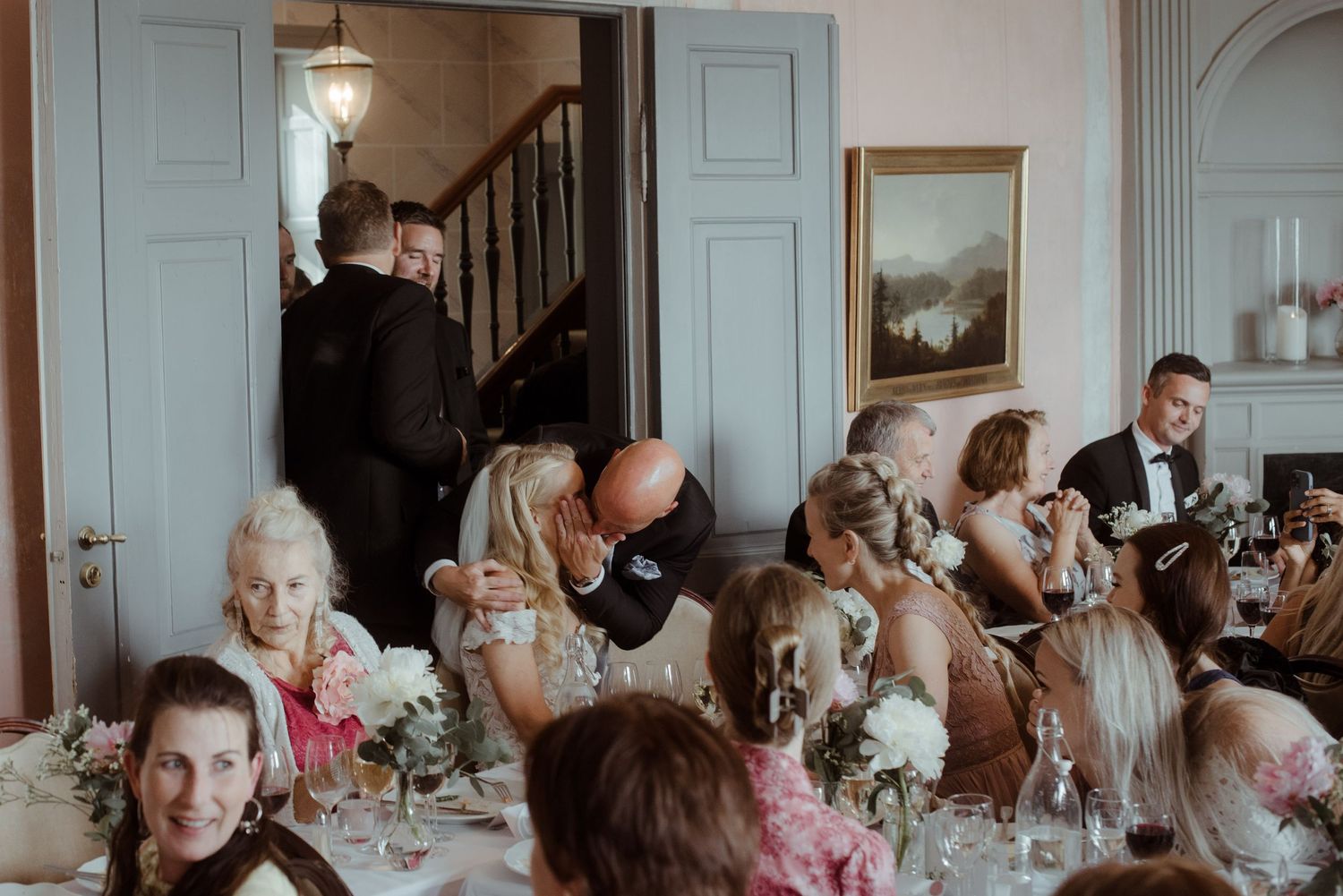 Guests seated at an elegant reception dinner with floral centerpieces and formal table settings.