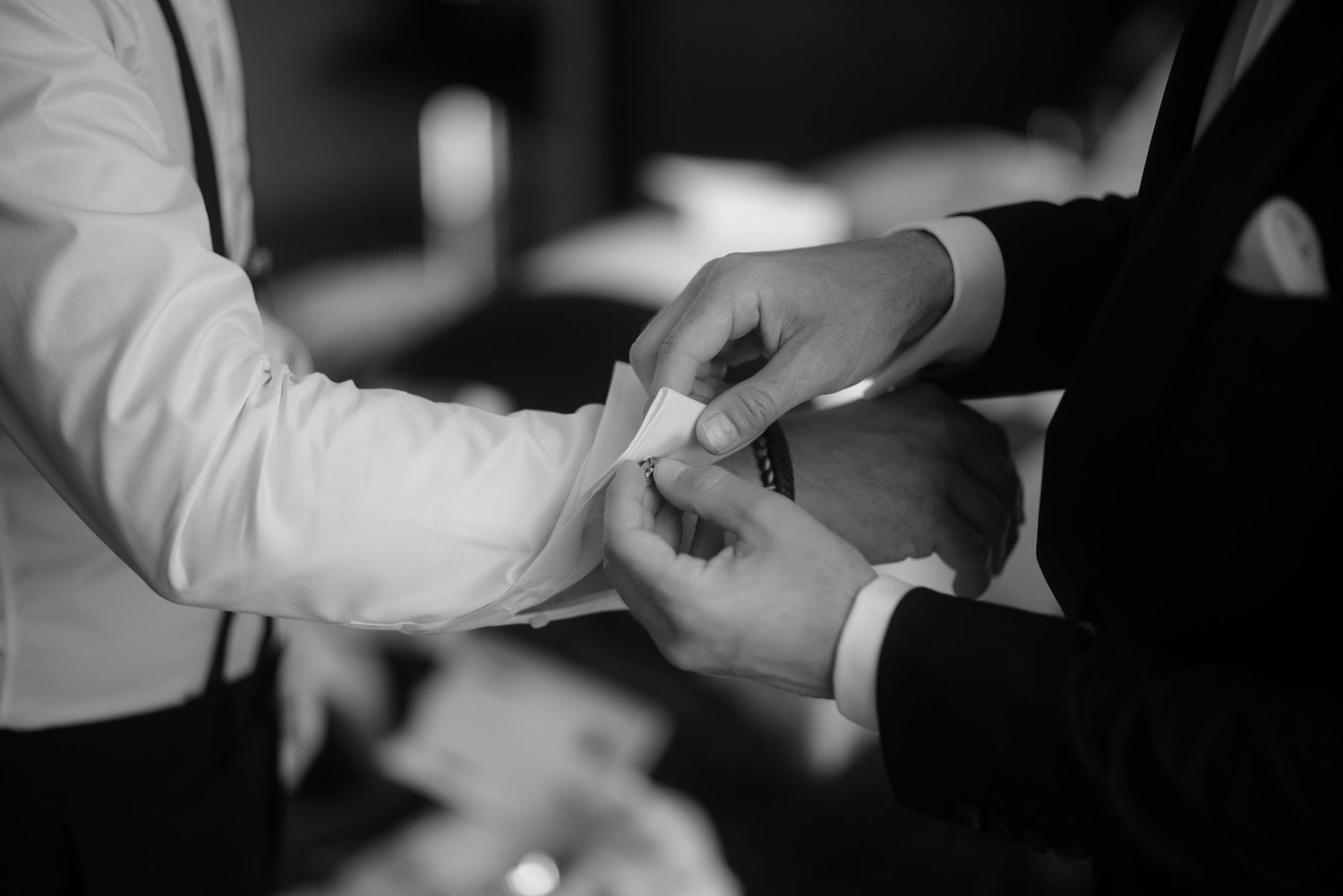Black and white close-up of hands exchanging rings during a wedding ceremony.