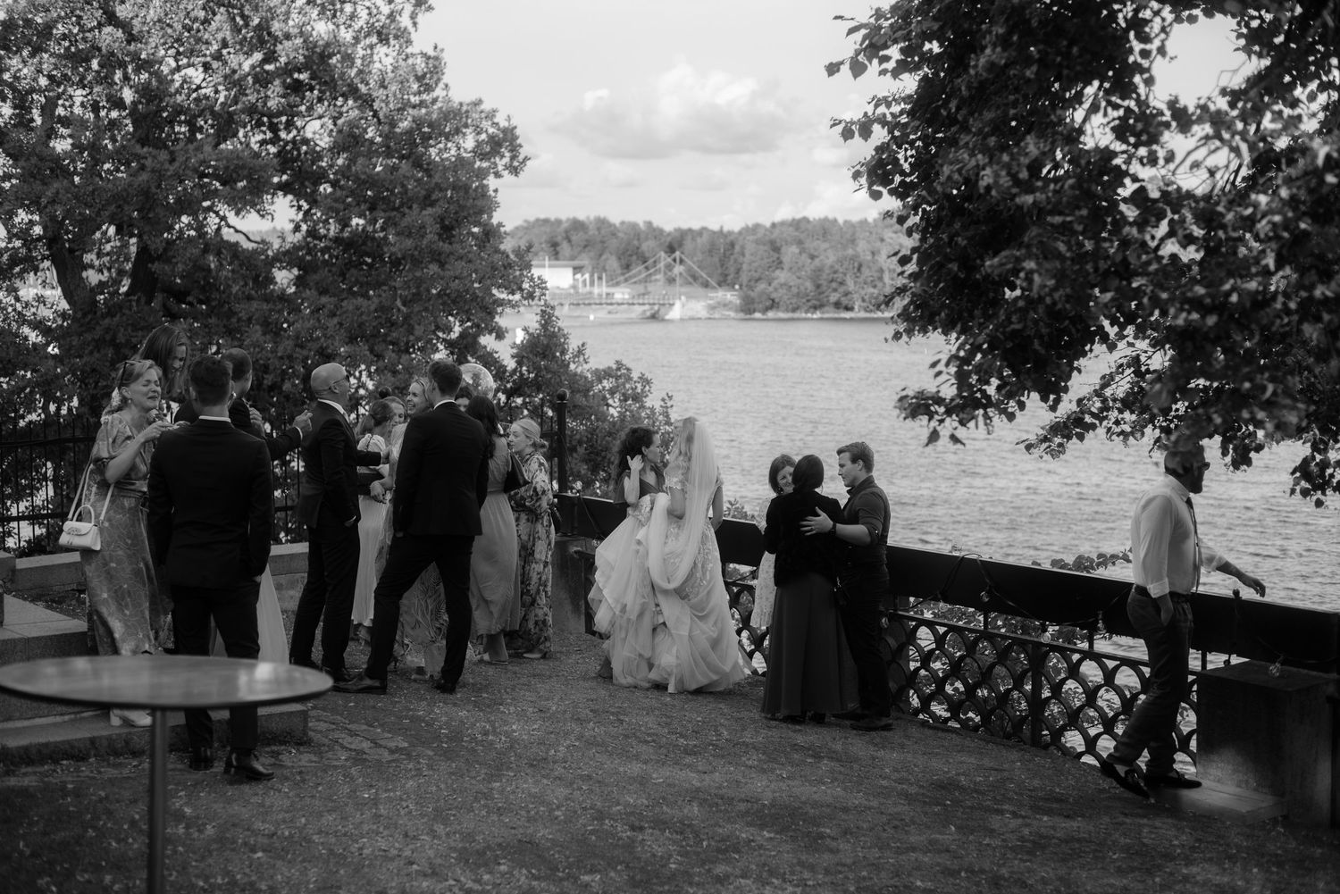Vintage black and white photo of guests gathered on a lakeside terrace.