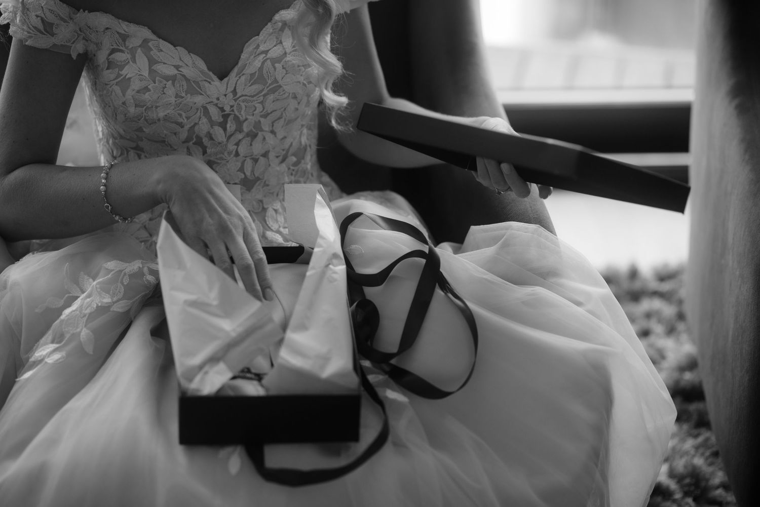 A detail shot of a white wedding dress with delicate lace details and black ribbons.