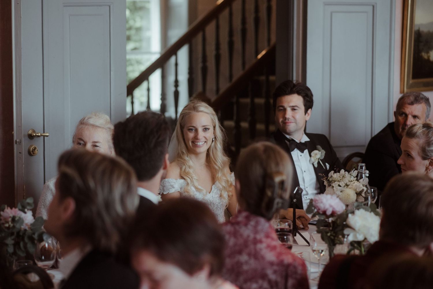 Wedding reception dinner in an elegant room with paneled walls and formal table settings.