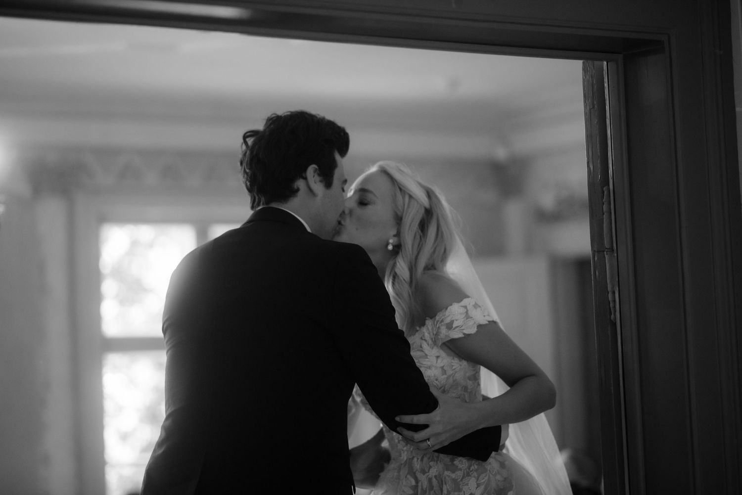 Black and white romantic moment captured in soft window light.