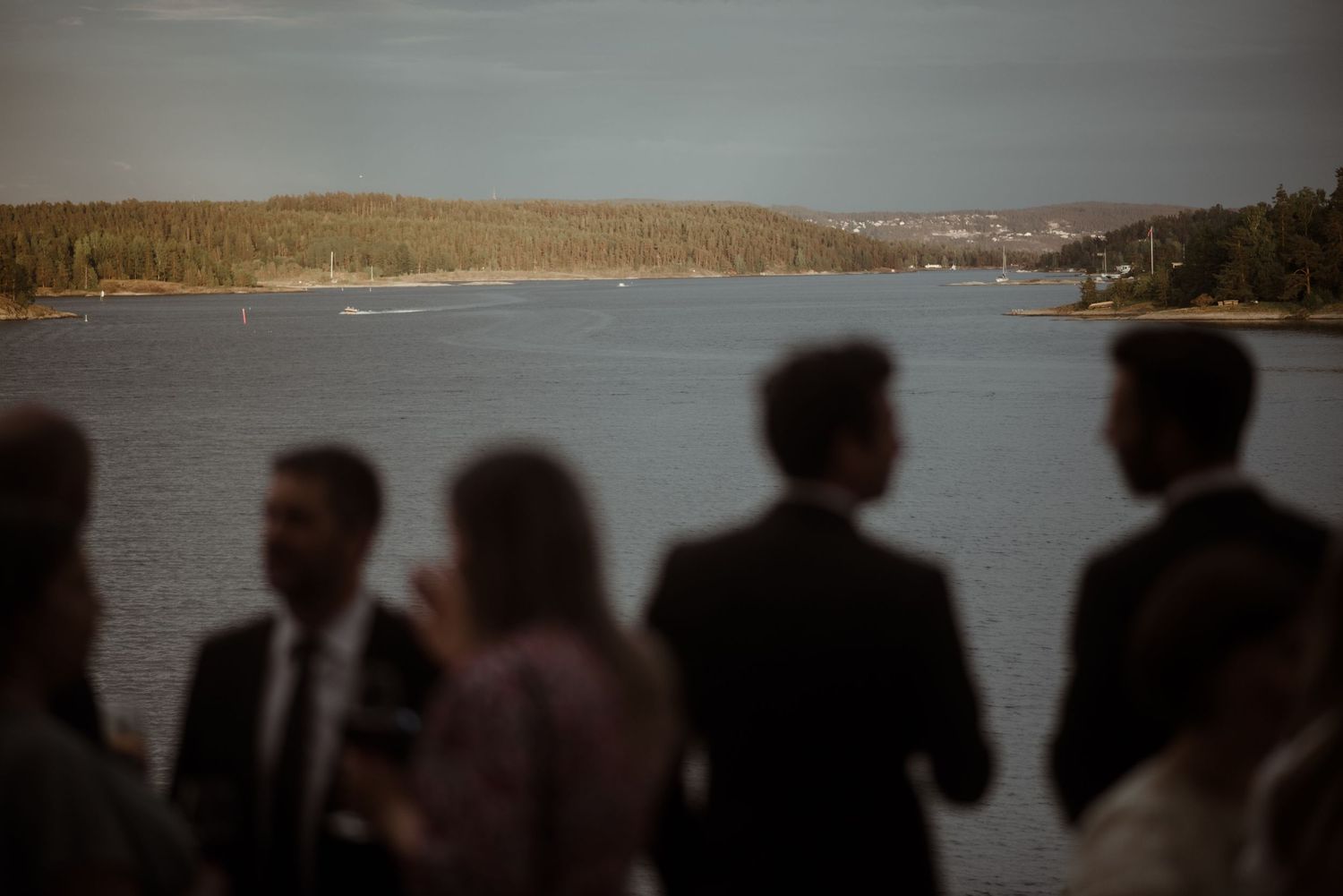 Silhouetted figures overlooking a scenic lake view at sunset.