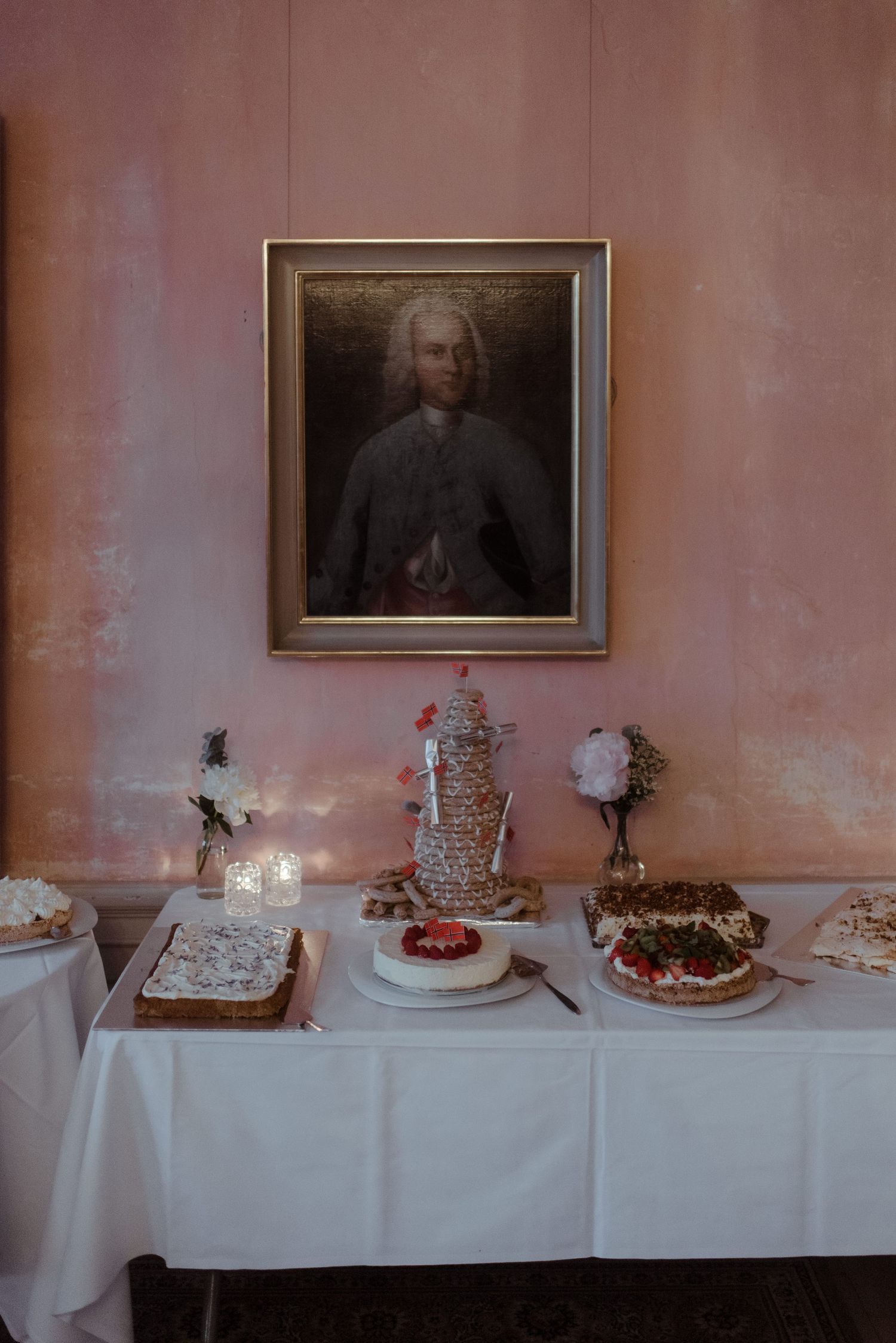 Formal dessert table with portrait painting and elegant white tablecloth setting.