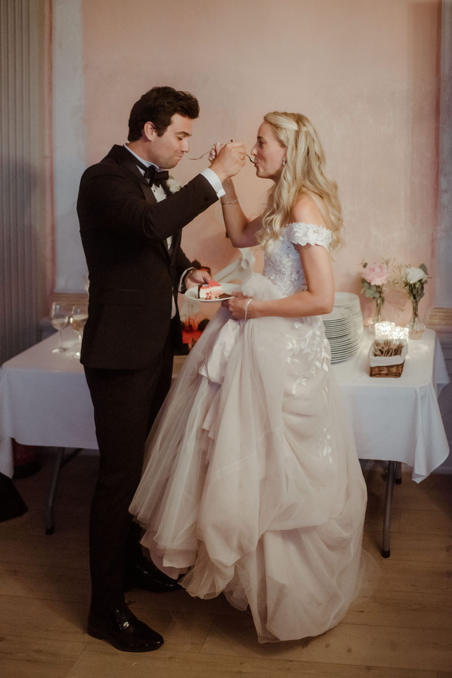 A couple playfully feeds each other cake during their wedding celebration.