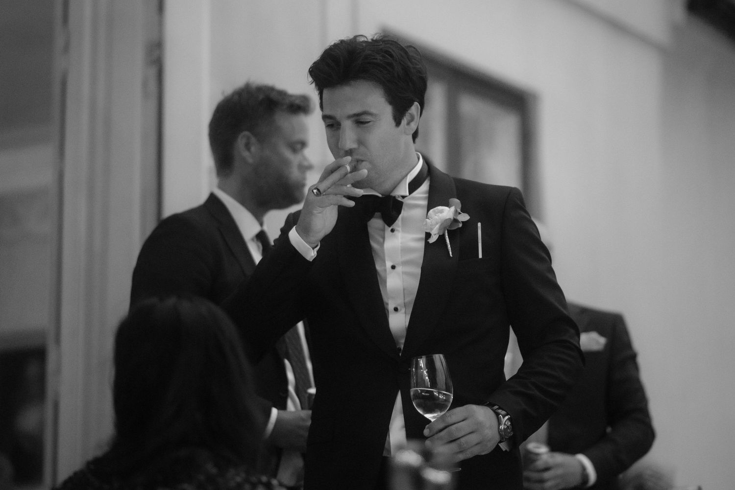 Two guests in tuxedos share a conversation at an elegant wedding reception.