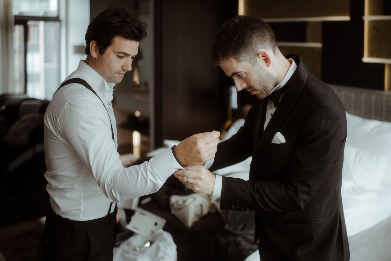 Two people in formalwear helping each other prepare for a special occasion.