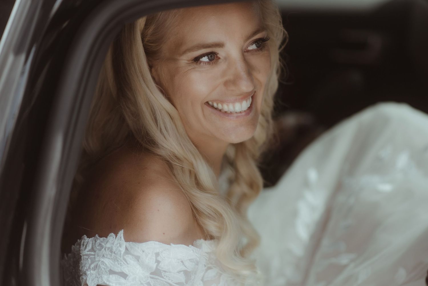 A joyful moment captured through a car window on a wedding day.
