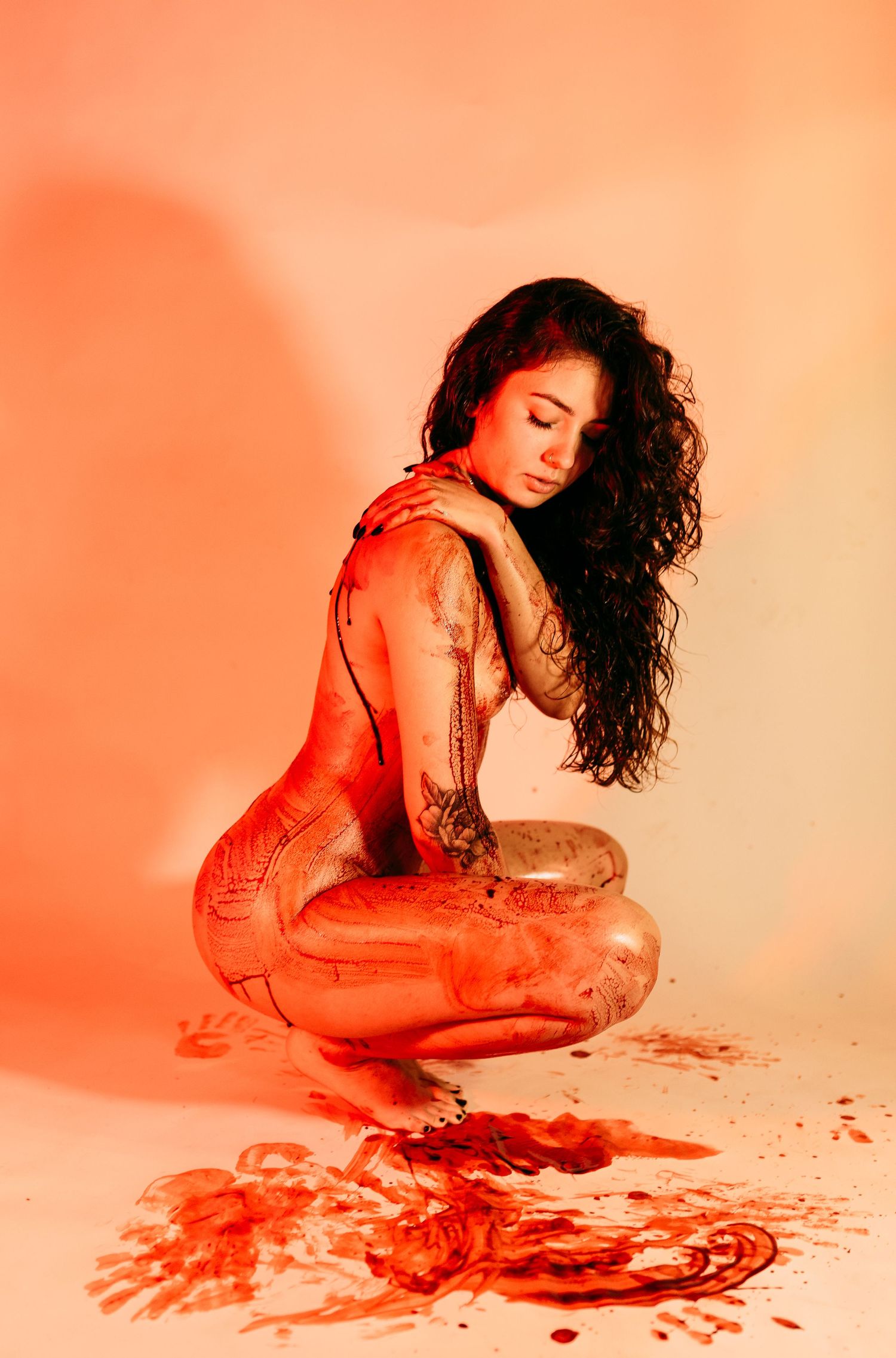 Artistic portrait with orange lighting and paint effects creating dramatic shadows.