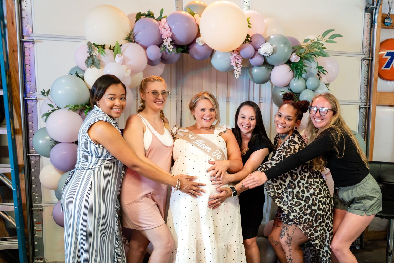 A celebratory group poses together under a pastel balloon arch baby shower and gender reveal photographer event coverage in upstate SC