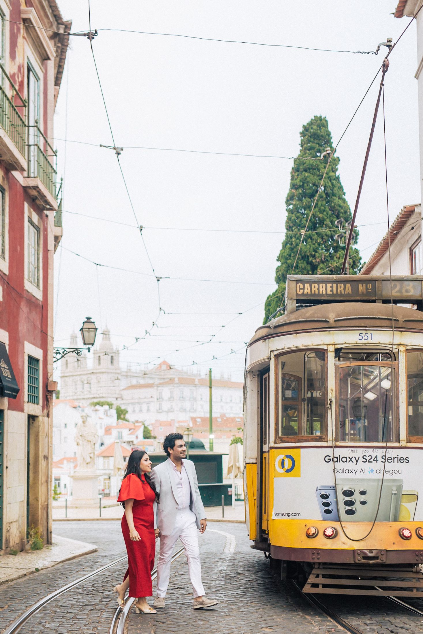 Engaged Indian couple embracing near iconic Lisbon architecture.