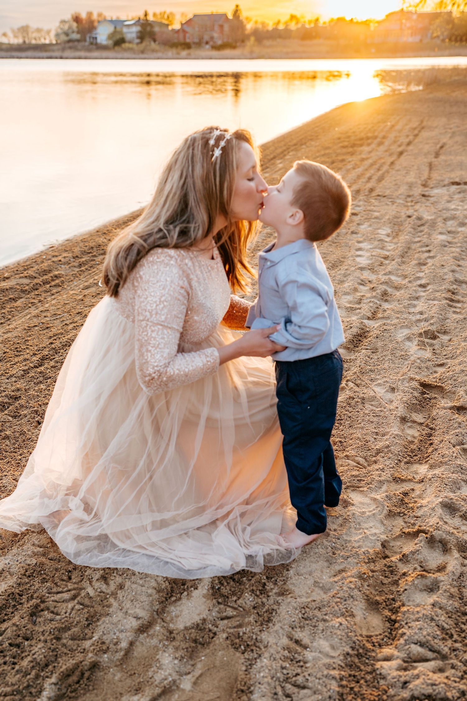 A tender sunset moment captured on a sandy beach with soft golden light reflecting off the water.