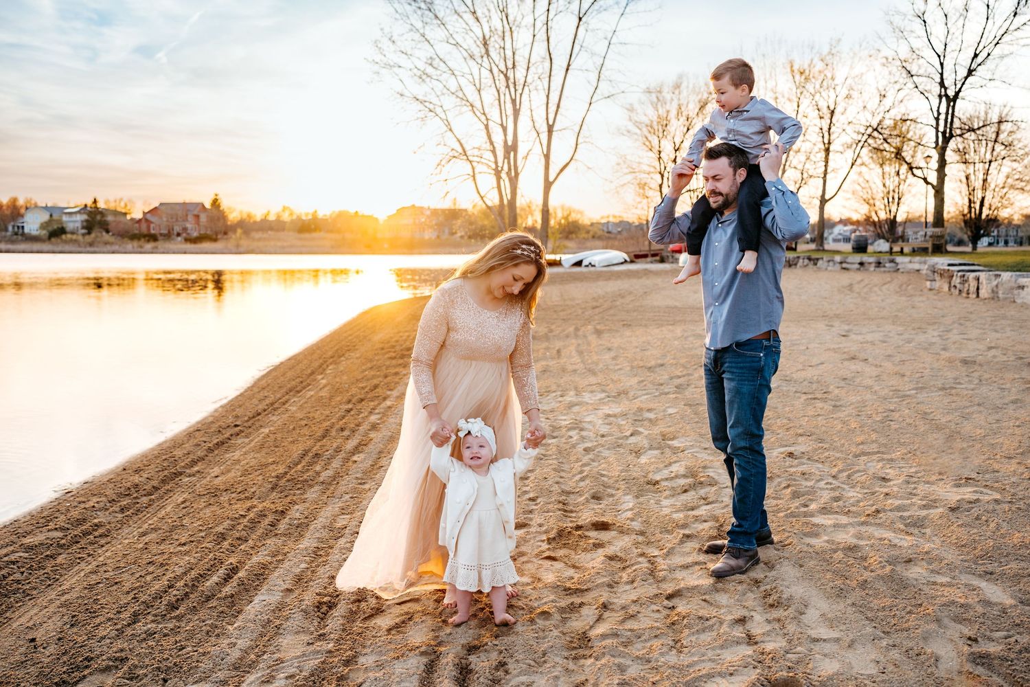 A family enjoying quality time together on a sandy beach at sunset beside a calm lake.