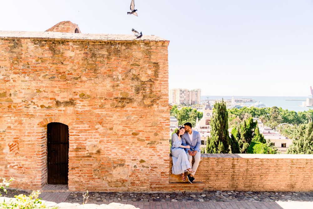 Couple enjoying scenic view from old brick terrace wall at historic Alhambra palace in Granada, Spain.