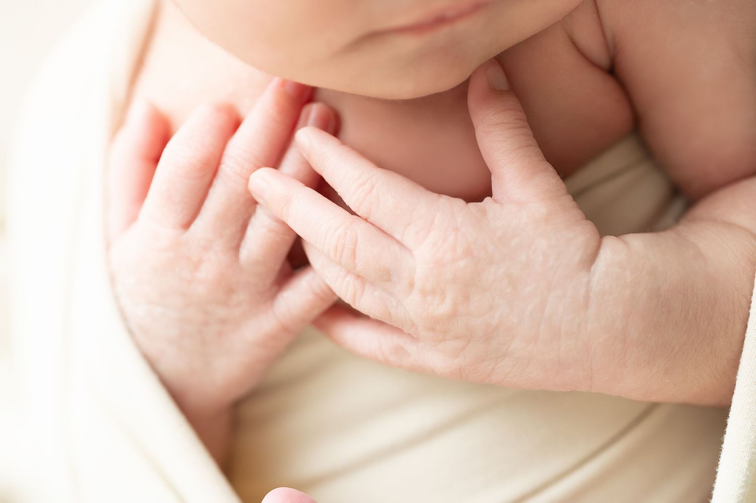 Delicate newborn hands and fingers against soft fabric.