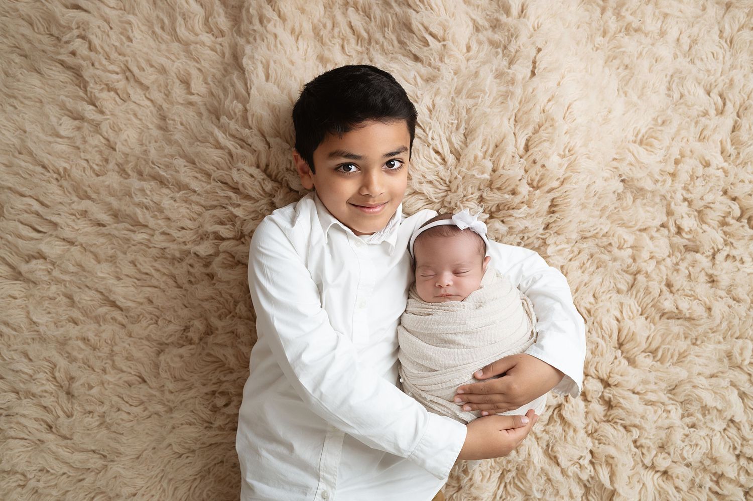 Siblings posed together on cream textured backdrop.