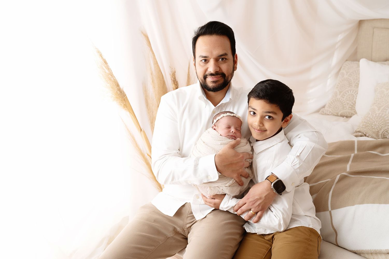 Family portrait with white outfits against light backdrop.