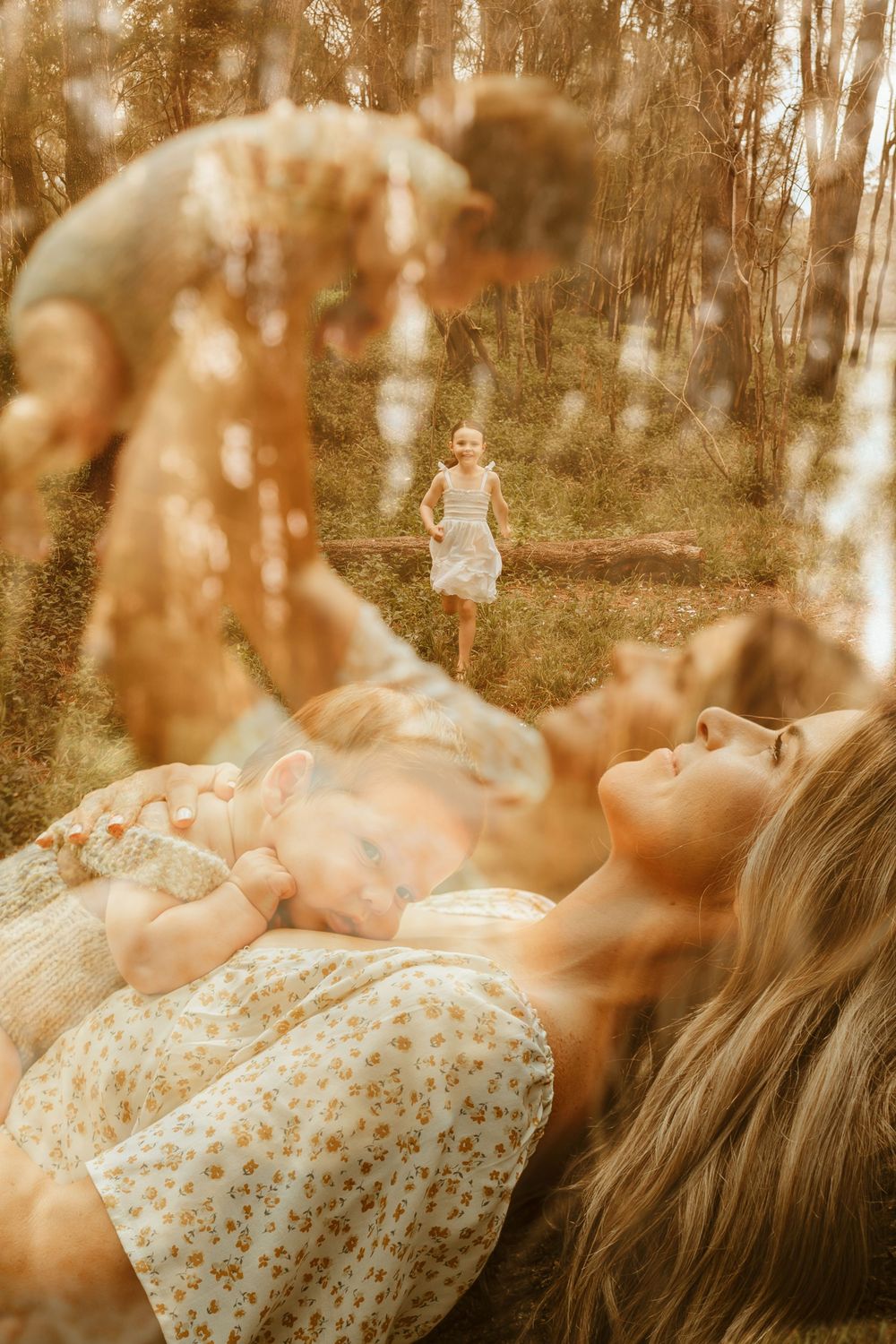 A person in a floral dress lies on the ground surrounded by autumn leaves creating a dreamy sepia-toned portrait.